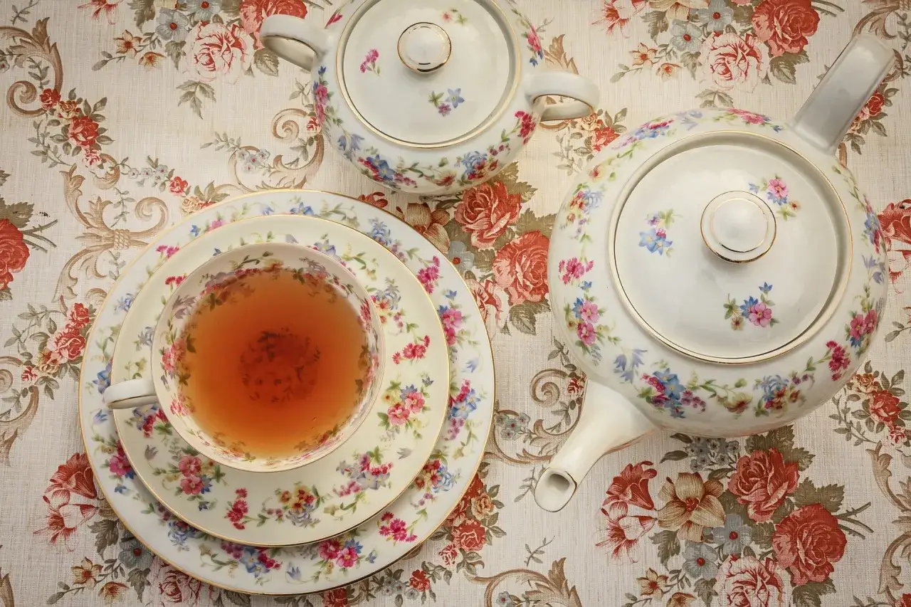Service &agrave; th&eacute; fleuri, une tasse remplie de th&eacute; ambr&eacute;, une th&eacute;i&egrave;re et un sucrier. Une belle tradition de tea time.