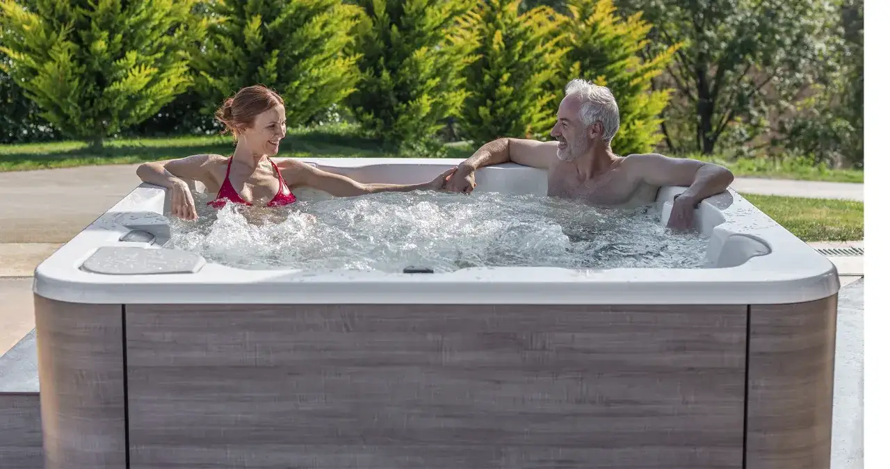 Un couple se tient la main dans un jacuzzi, profitant d'un moment de d&eacute;tente. Ils semblent se demander combien de temps dans un jacuzzi est id&eacute;al pour se relaxer.