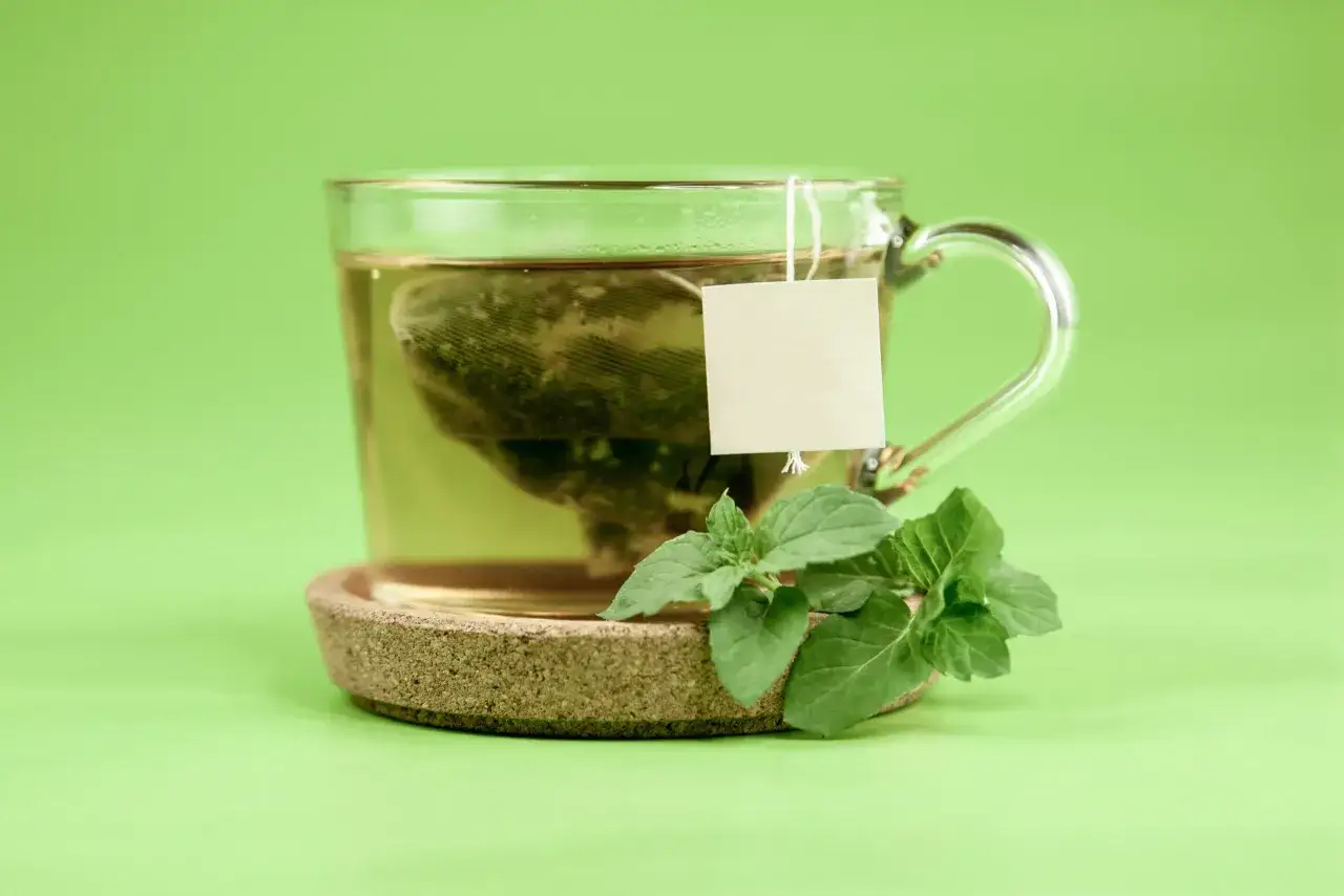 Tasse de th&eacute; vert avec des feuilles de menthe, rappelant les cat&eacute;chine bienfaits pour la sant&eacute;.